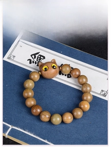 Vue macro d'un bracelet en perles de bois avec sculpture de chat sur un livre ancien