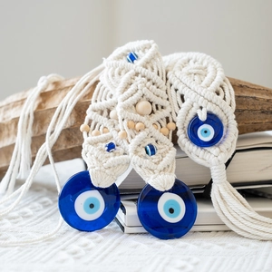 Detail of handcrafted macrame evil eye wall hanging with blue glass and wooden beads