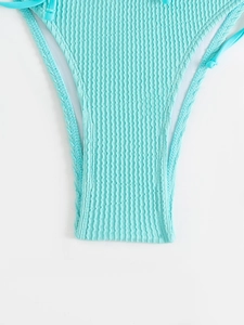Macro detail of light blue ribbed bikini bottom with side ties and fine vertical texture