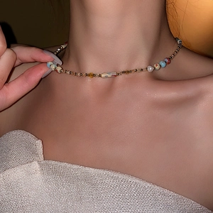 Detail of a choker necklace with amber beads and gold accents on a model's neck