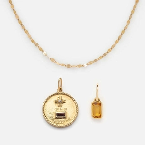 Detail of gold necklace with red round gemstone and yellow rectangular zircon pendant