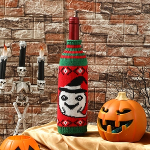 Detail of a knitted Halloween wine bottle cover with a white ghost and witch hat design