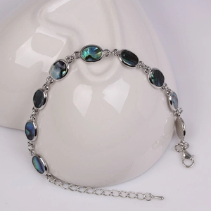 Detail view of silver heart cross bracelet with oval abalone shell on heart tray