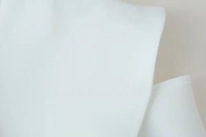 Close-up of white high-density woven fabric texture showing the premium suit material detail