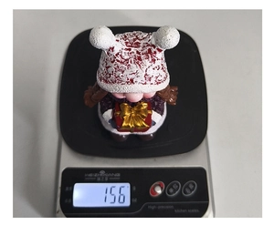 Christmas gnome girl figurine on a digital scale showing a precise weight of 156 grams