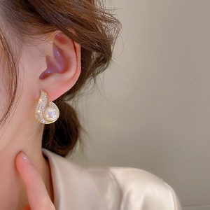 Macro shot of gold-plated mermaid pearl earrings with zircon waterdrop design on ear