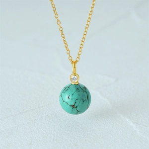 Close-up of a s925 gold necklace featuring a spherical turquoise stone pendant on fine chain