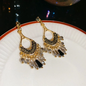 Close-up of vintage bohemian tassel earrings with emerald beads and dark crystal drops
