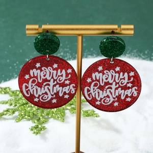 Close-up of glittery red and green Merry Christmas earrings on a golden display stand