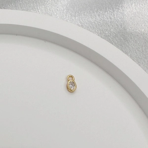Close-up of a golden oval pendant with a faceted clear crystal for DIY jewelry