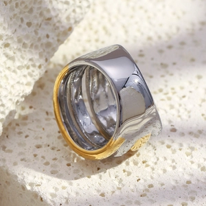 Detailed view of dual-tone wide stainless steel ring on natural coral stone texture