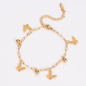 Macro shot of gold butterfly charms and polished beads on stainless steel bracelet