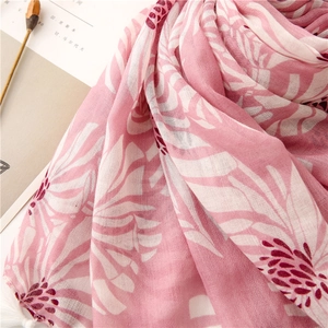 Détail d'une écharpe florale rose avec texture coton-lin fine et glands à franges