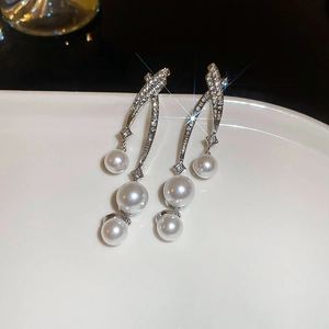 Gros plan de boucles d'oreilles en argent avec cristaux et perles blanches graduées