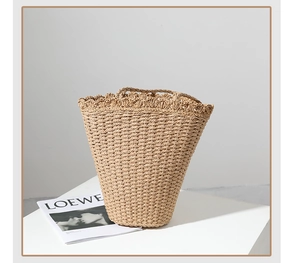 Close-up of handwoven straw bag with elegant scalloped crochet trim on a white podium