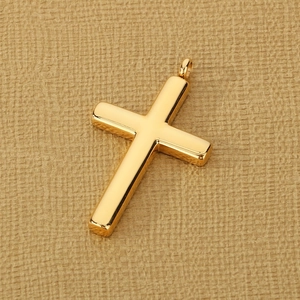 Close-up of polished gold stainless steel cross pendant on warm textured paper background