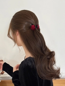 Detail of a red rose flower hair claw clip styling a half-up hairstyle on a woman