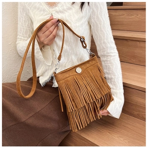 Close-up of brown suede crossbody bag with fringe tassel details worn by a model