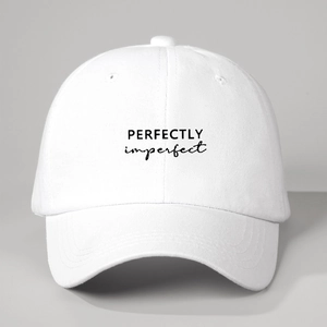 Close-up of white washed cotton baseball cap featuring Perfectly Imperfect printed text
