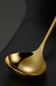 Close-up of golden stainless steel soup spoon showing polished edges and mirror finish