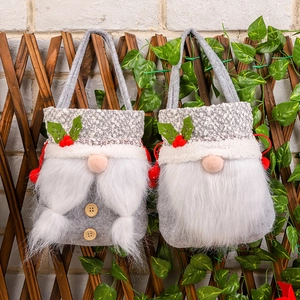 Two grey Christmas gnome gift bags with felt fabric and plush beard on wooden background