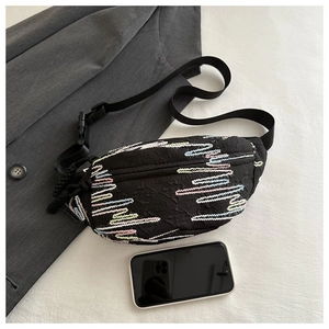 Detail of black crossbody bag featuring embossed wave patterns and adjustable nylon strap