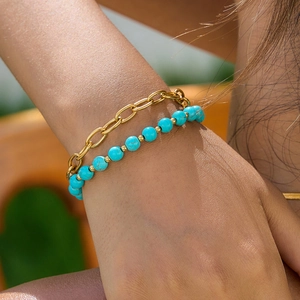 Close-up of gold chain and turquoise beaded bracelet set worn on a female wrist
