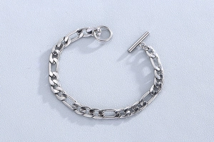 Détail d'un bracelet chaîne Figaro argenté avec fermoir classique en métal OT et barre T