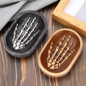 Gothic skull hand resin soap dish with drainage holes on a vintage wooden background