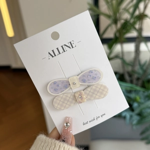 Detail of floral and checkered hair clips set with rhinestone accents on display card