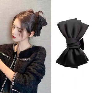 Close-up of a large black satin bow hair claw clip for elegant French style hairstyles