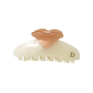 Detail view of heart design hair claw clip in cream and peach with golden D letter
