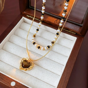 Detail of gold plated tiger eye heart pendant and beaded necklace in a wood jewelry box