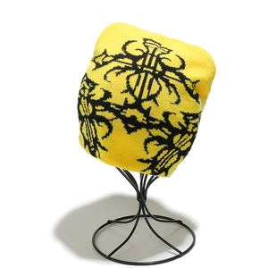 Dettaglio del berretto in maglia giallo con motivi jacquard gotici neri e trama tessuta