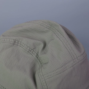 Vue macro du tissu ripstop respirant avec coutures renforcées sur un chapeau de soleil gris-vert
