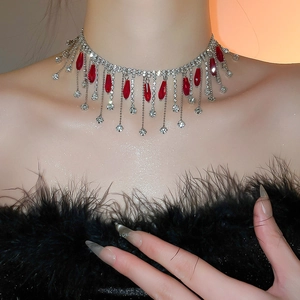 Close-up of vintage style necklace with silver fringe, red rhinestones and crystals