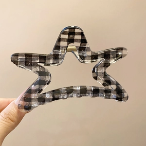 Detail of star-shaped hair claw clip with classic black and white gingham grid pattern
