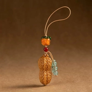 Macro detail of sandalwood keychain featuring realistic peanut and persimmon charms