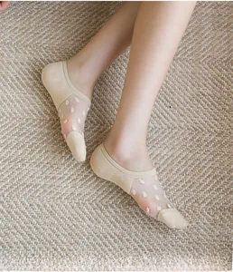 Close-up of beige sheer low-cut boat socks with velvet polka dots on woven mat