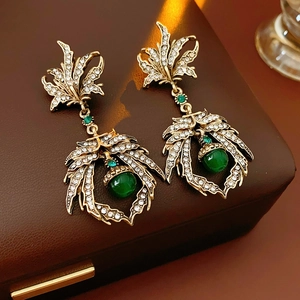 Détail des boucles d'oreilles vintage dorées avec perles vertes et strass