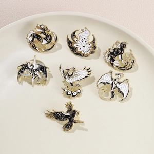 Collection of seven black and white enamel pins with mythical creatures in a ceramic dish