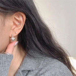 Detailed view of polished sterling silver heart earrings worn by a model in casual style
