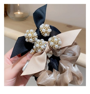 Détail d'un chouchou élégant en satin noir et organza de champagne avec perle et strass