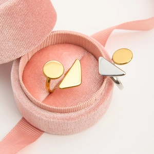 Geometric stainless steel rings in gold and silver finish inside a pink velvet jewelry box
