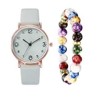 Close-up of a women's quartz watch with a light green leather strap and beaded bracelet