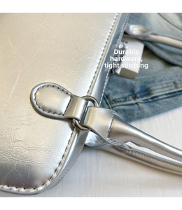 Detail showing high-quality silver metal buckle and tight stitching on silver leather bag