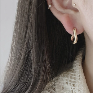 Close-up of golden minimalist U-shaped twisted earrings worn by a model in a lifestyle setting