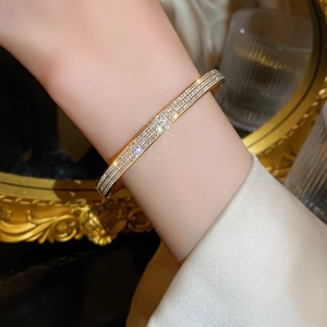 Dettaglio di un bracciale dorato con zirconi incastonati indossato da una modella