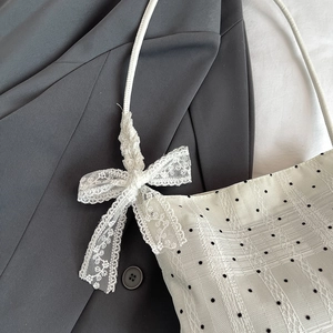 Polka dot jacquard bucket bag featuring elegant white lace bow strap detail on grey blazer
