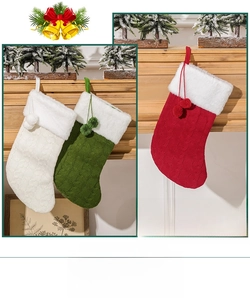 Detail of knitted Christmas stockings with plush cuffs and pom-poms on a wooden mantel